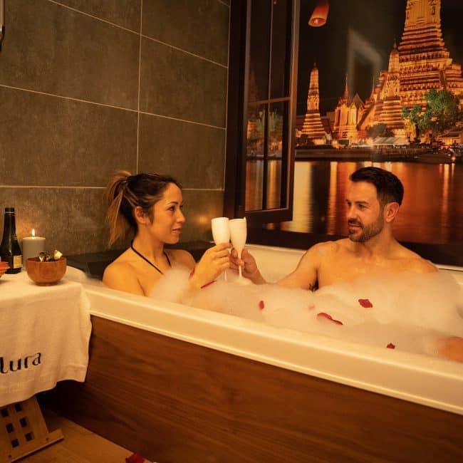 Pareja en jacuzzi spa con copa de cava en Alura